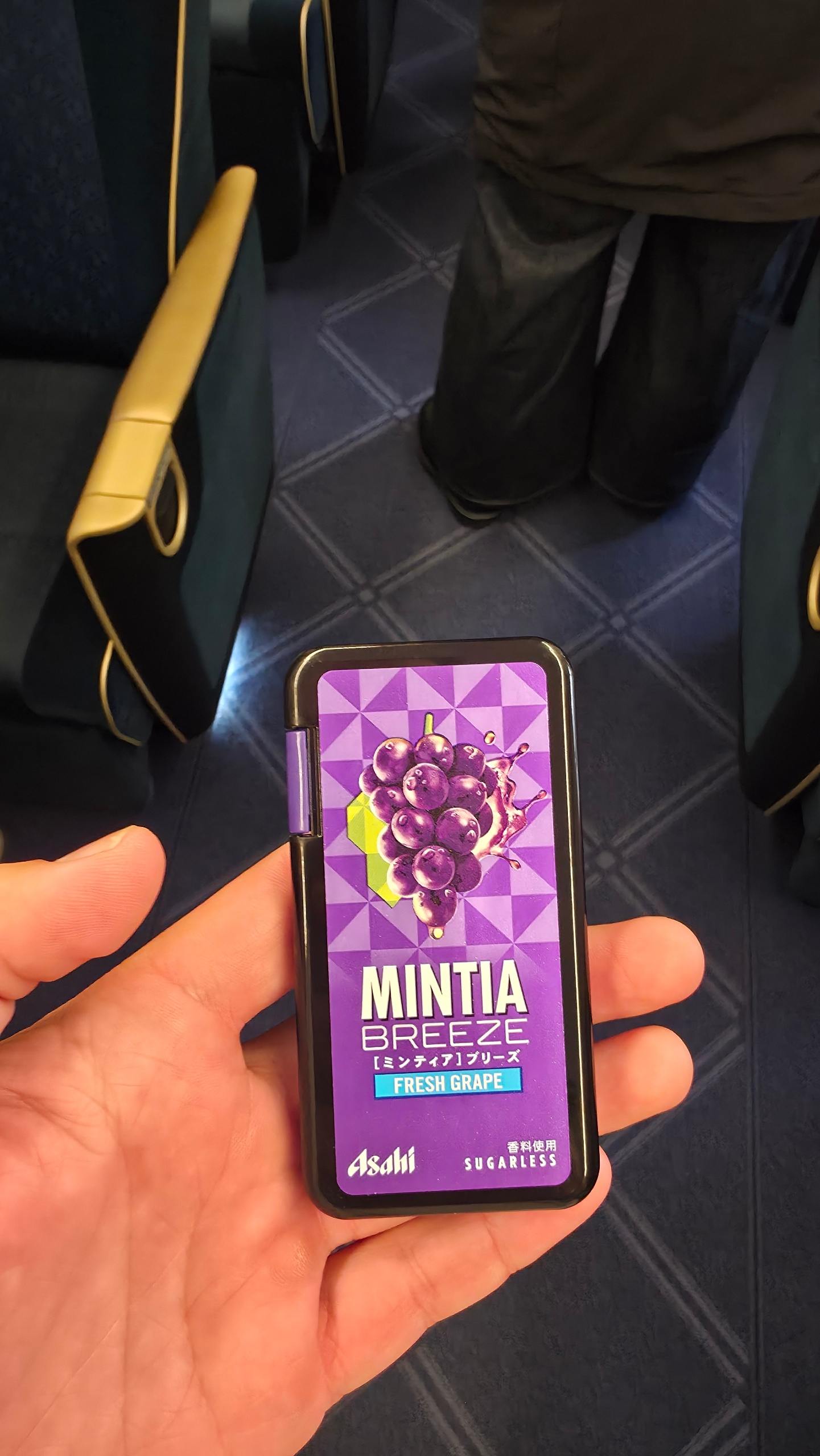 Original Mintia Breeze candy package design with white text and a purple grape illustration on a geometric purple background logo featuring purple, black, blue colours