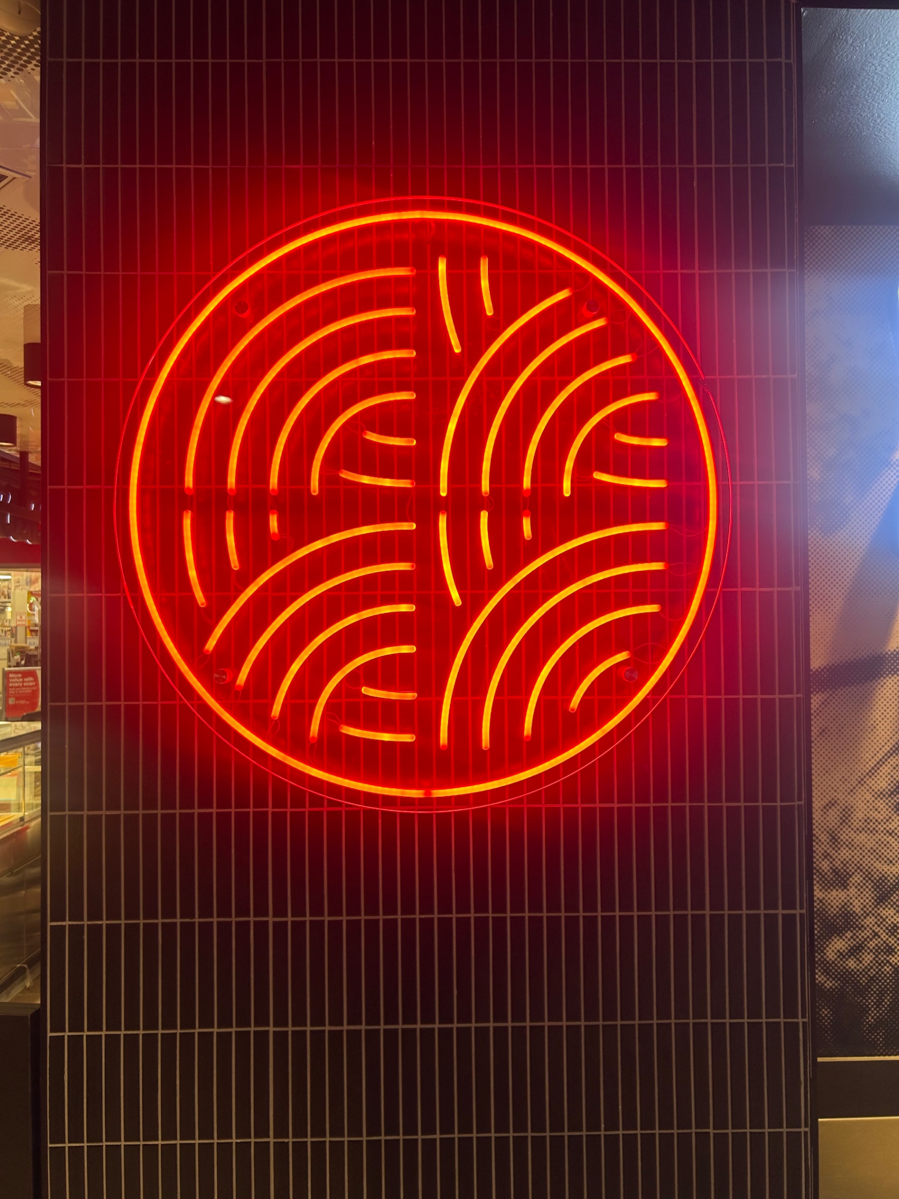 Original red circular maze-like icon composed of curved segmented lines inside a circle logo featuring red, black, dark brown colours