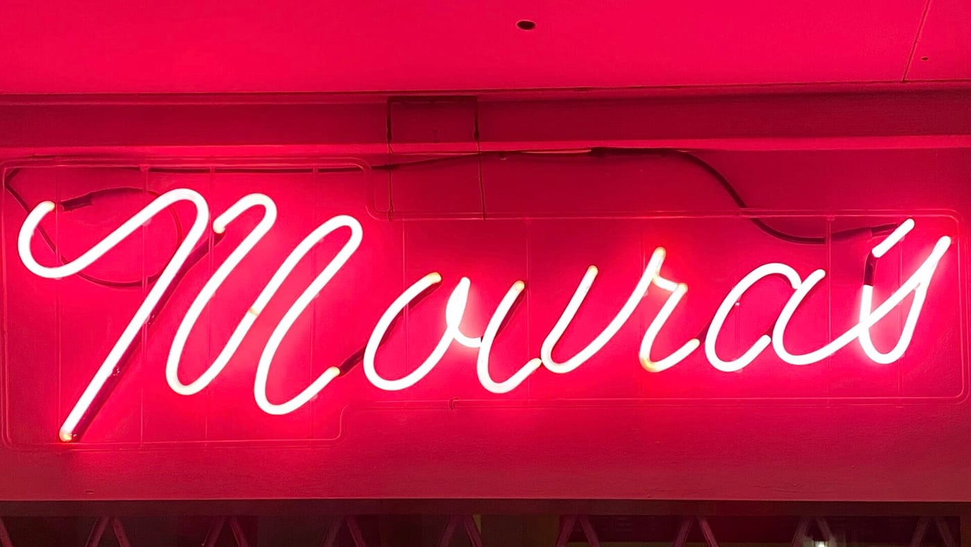 Original white neon script text 'Mouras' on a pink background logo featuring pink, white, black colours