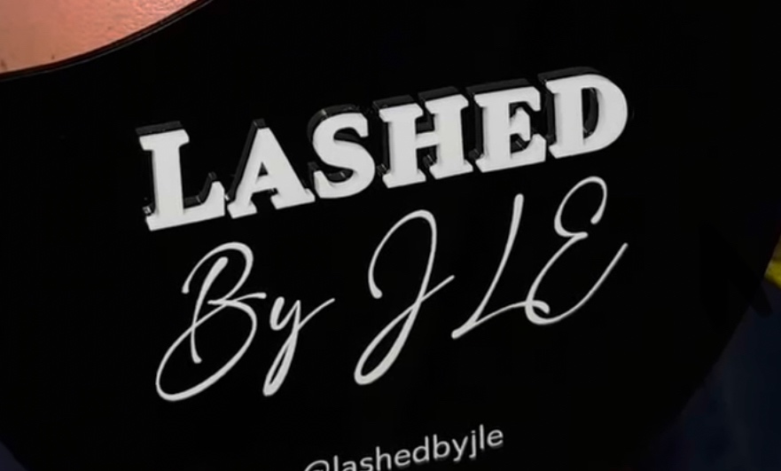 Original white text logo reading 'LASHED By JLE' with smaller '@lashedbyjle' handle on a black background logo featuring black, white, pink colours